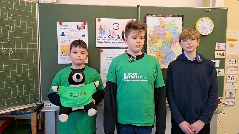 Unsere Kinderreporter vor einer Schultafel